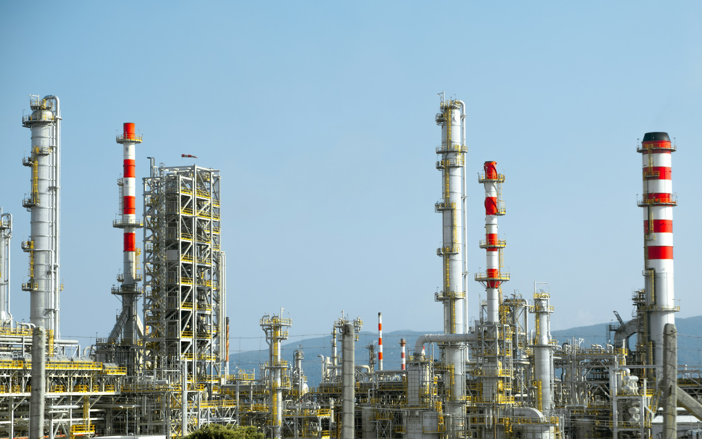 Refinery towers under a blue sky, illustrative